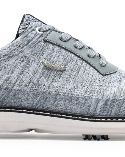Men's Challenger Shoe in Carbon, close-up side view featuring a heathered gray knit upper highlighting the silver wing logo badge, gray leather lace stay, and black welt stitch detail with white midsole and spiked outsole