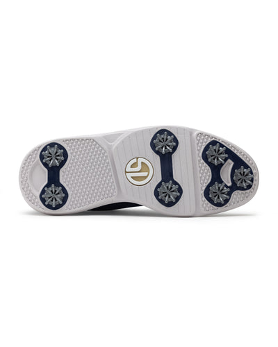 Men's Challenger Shoe in Indigo, bottom sole view featuring a white rubber outsole with navy spike cleats, textured traction zones, and a gold and white branded logo badge