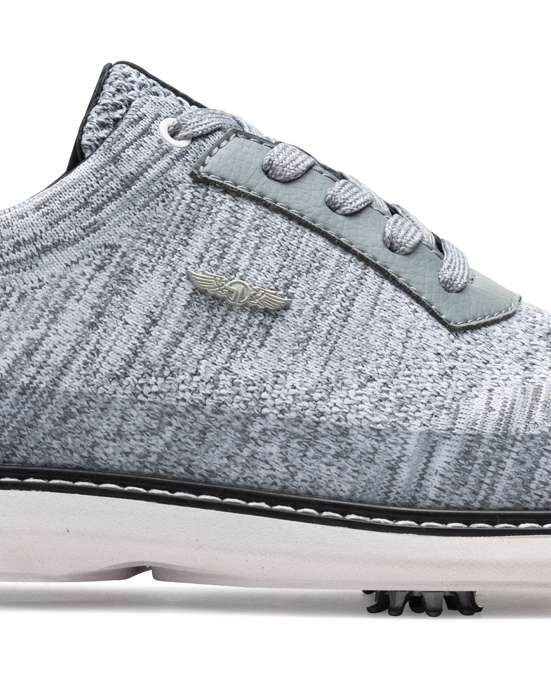 Men's Challenger Shoe in Carbon, close-up side view featuring a heathered gray knit upper highlighting the silver wing logo badge, gray leather lace stay, and black welt stitch detail with white midsole and spiked outsole
