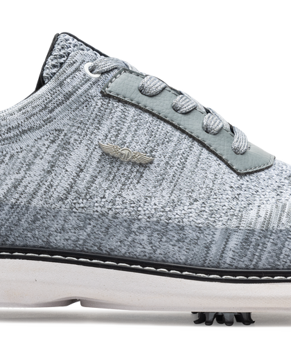Men's Challenger Shoe in Carbon, close-up side view featuring a heathered gray knit upper highlighting the silver wing logo badge, gray leather lace stay, and black welt stitch detail with white midsole and spiked outsole