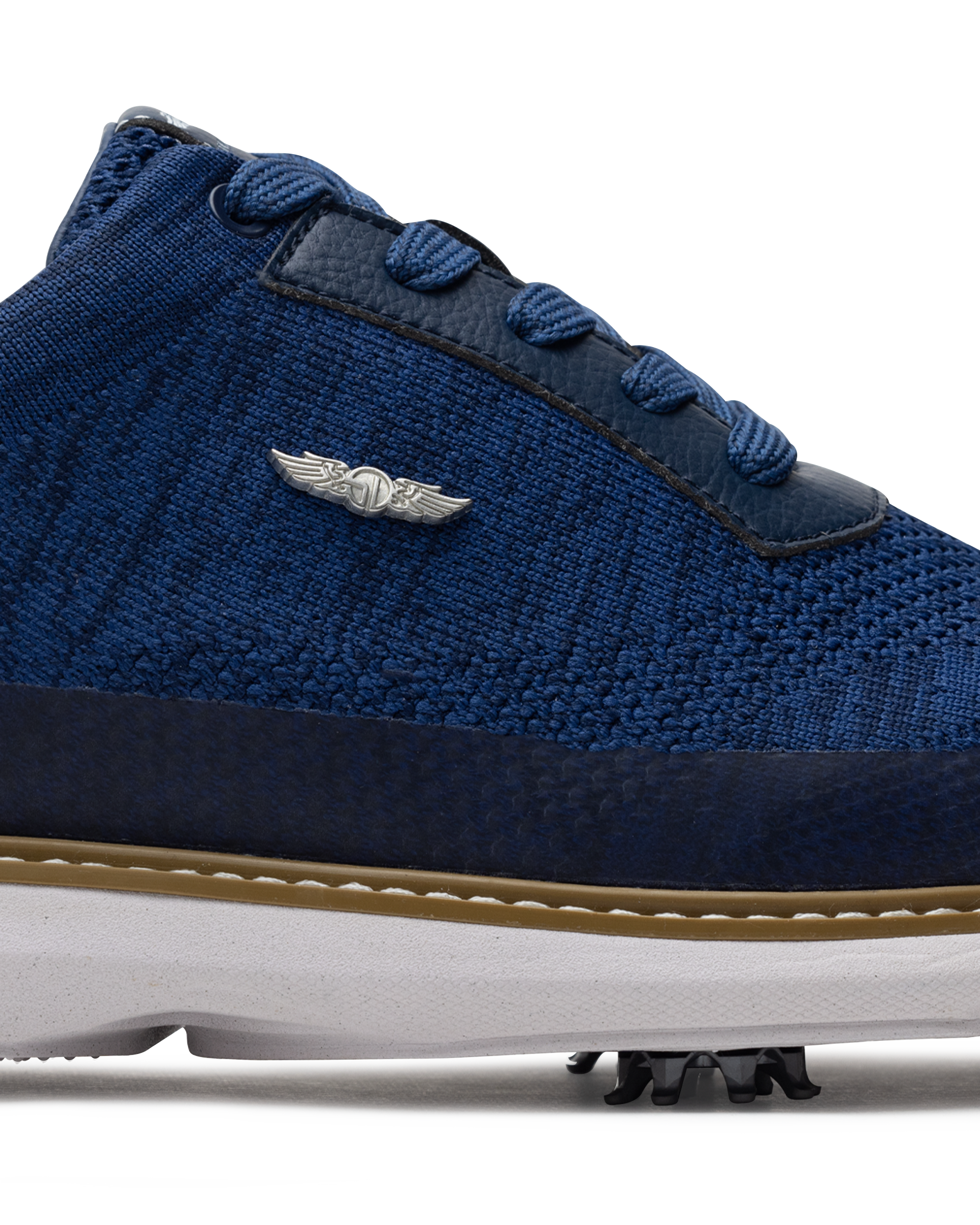 Men's Challenger Shoe in Indigo, close-up side view featuring a navy knit upper highlighting the silver wing logo badge, navy leather lace stay, and tan welt stitch detail with white midsole and spiked outsole