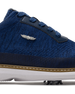 Men's Challenger Shoe in Indigo, close-up side view featuring a navy knit upper highlighting the silver wing logo badge, navy leather lace stay, and tan welt stitch detail with white midsole and spiked outsole