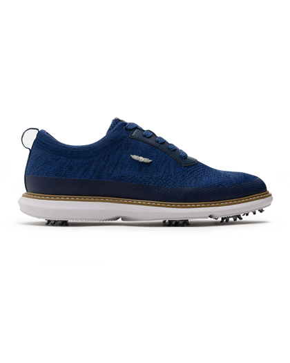 Men's Challenger Shoe in Indigo, side profile view featuring a navy knit upper with navy laces, a silver wing logo badge, navy leather trim, a tan welt stitch detail, white midsole, and spiked outsole