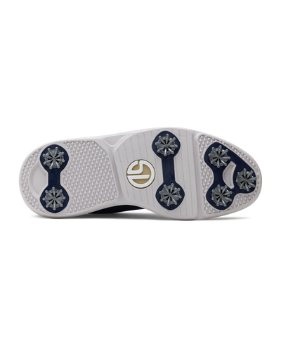 Men's Challenger Shoe in Indigo, bottom sole view featuring a white rubber outsole with navy spike cleats, textured traction zones, and a gold and white branded logo badge