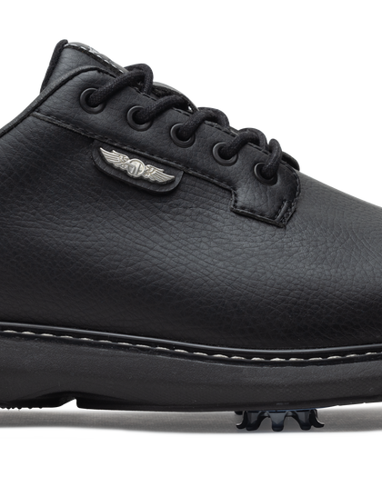 Men's Derby Shoe in Black, close-up side view featuring black pebbled leather upper with silver winged Straight Down logo badge on tongue tab, black lacing system, contrast stitch midsole trim, and spiked outsole