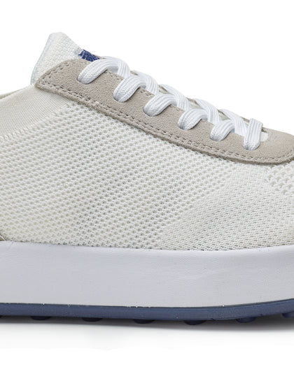 Men's Rally Shoe in White, detail close-up view featuring the white knit upper texture, light gray suede overlay at the toe box, white lace-up closure, and white midsole with navy outsole visible at the base