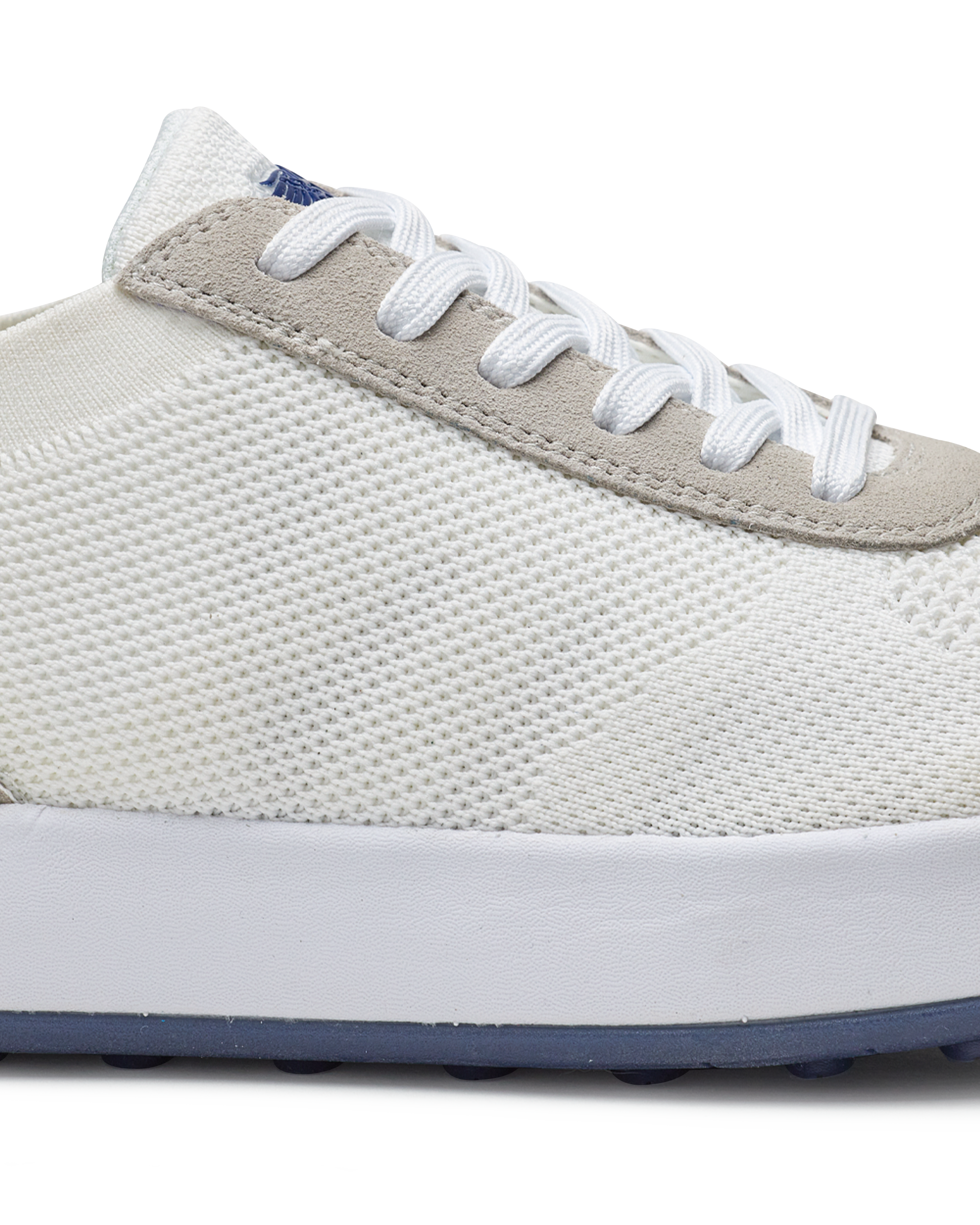 Men's Rally Shoe in White, detail close-up view featuring the white knit upper texture, light gray suede overlay at the toe box, white lace-up closure, and white midsole with navy outsole visible at the base