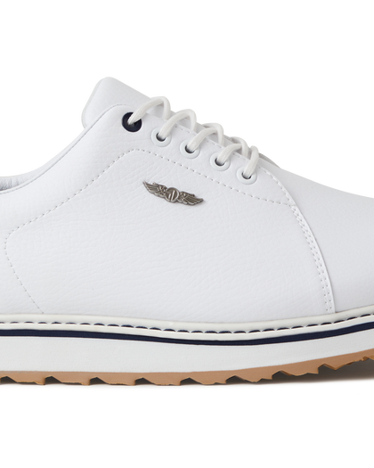 Straight Down Bourbon Hybrid Golf Shoe in White, close-up lateral side detail view featuring white pebbled leather upper, silver Straight Down wing logo badge, navy lace eyelet accents, white laces, white midsole with navy stripe accent, and gum traction outsole