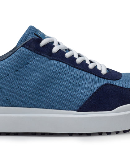 Straight Down Boardwalk Golf Shoe in Petrol, close-up lateral side detail view featuring medium blue canvas upper, navy suede lace overlay and heel panel, white laces, and white outsole