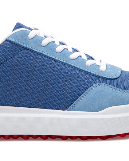 Straight Down Boardwalk Golf Shoe in Federal, close-up lateral side detail view featuring medium blue canvas upper, light blue suede lace overlay and heel panel, white laces, and red traction outsole