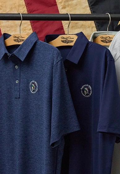 Men’s 126th U.S. Open polos in heather navy and navy hanging on wooden hangers with embroidered championship logos