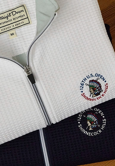 Close-up of Optic Quarter Zip golf pullovers (white & navy) with embroidered “126th U.S. Open Shinnecock Hills” logo detail 