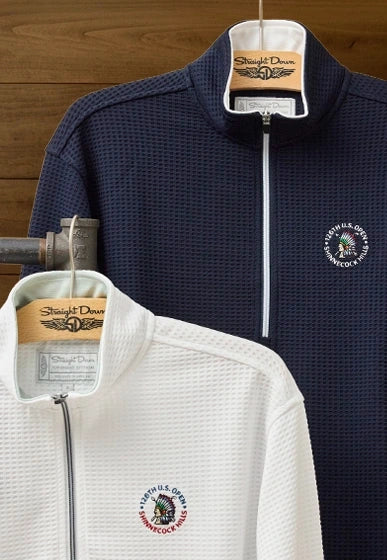 Women’s 126th U.S. Open Opal Half Zip  in white and navy hanging on wooden hangers with embroidered championship logos
