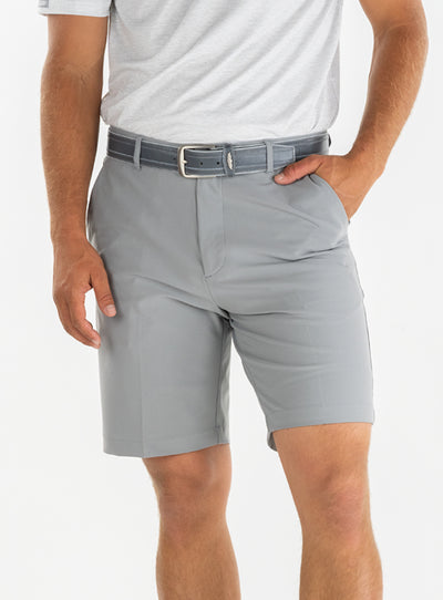 Men's Drake Short in Carbon, front model view featuring a flat-front silhouette in a cool medium gray colorway, styled with a gray belt and gray polo