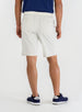 Men's Drake Short in Stone, back model view featuring button-welt back pockets in a warm off-white colorway, styled with a navy polo and navy golf shoes