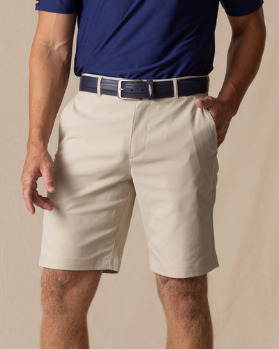 Men's Maverick Twill Short in Cashew, front model view featuring a light tan solid twill fabric with side slash pockets, styled with a navy polo and navy belt