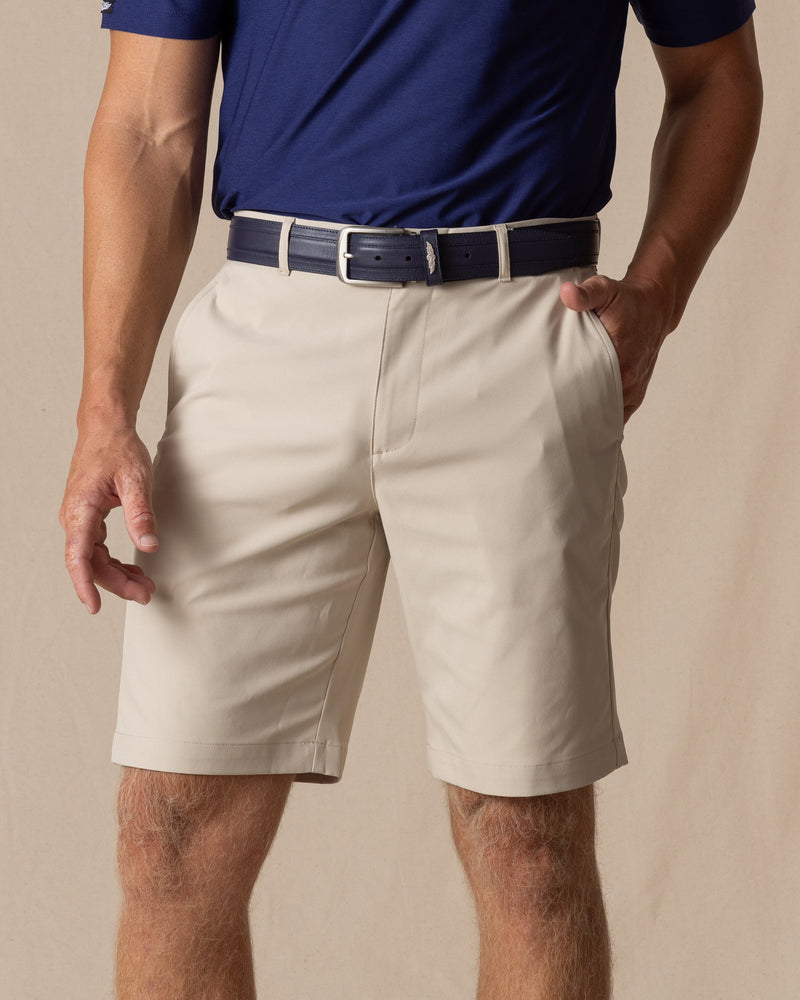 Men's Maverick Twill Short in Cashew, front model view featuring a light tan solid twill fabric with side slash pockets, styled with a navy polo and navy belt