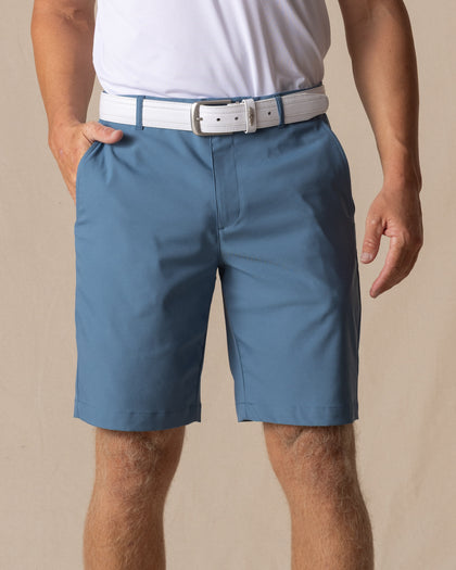 Men's Maverick Twill Short in Petrol, front model view featuring a medium blue solid twill fabric with side slash pockets , styled with a white polo and white belt