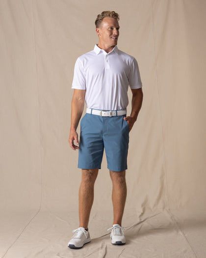 Men's Maverick Twill Short in Petrol, full length model view featuring a medium blue solid twill fabric, styled with a white polo, white belt, and white shoes