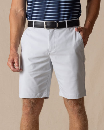 Men's Maverick Twill Short in Silver, front model view featuring a light gray solid twill fabric with side slash pockets and belt loops, styled with a navy striped polo and black belt