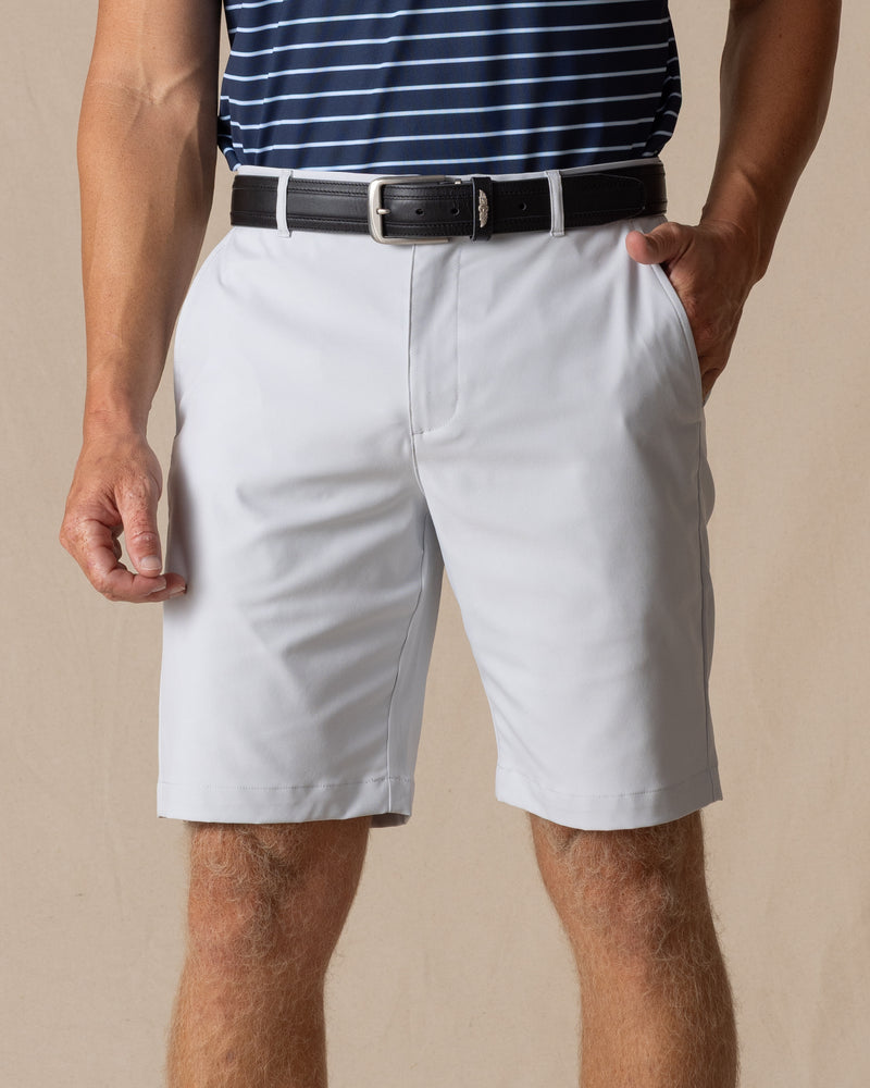 Men's Maverick Twill Short in Silver, front model view featuring a light gray solid twill fabric with side slash pockets and belt loops, styled with a navy striped polo and black belt