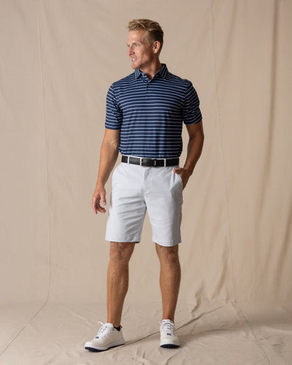 Men's Maverick Twill Short in Silver, full length model view featuring a light gray solid twill fabric with belt loops, styled with a navy striped polo, black belt, and white shoes