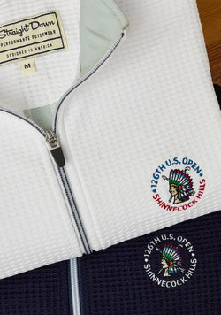 Close-up of white and navy Optic quarter-zip with waffle knit texture featuring the embroidered 126th U.S. Open Shinnecock Hills logo