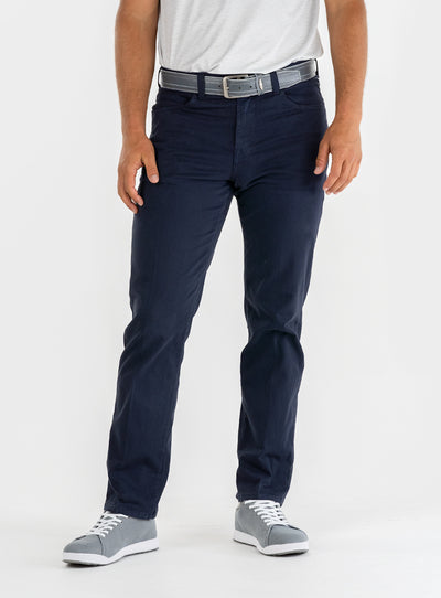Men's Clemson Pant in Indigo, on-model front view featuring a navy five-pocket style with a button closure and gray belt worn with a white tee and gray golf shoes