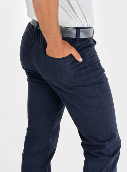 Men's Clemson Pant in Indigo, on-model close-up side view featuring a navy five-pocket style with a rear pocket, tonal embroidered logo, and a gray belt with silver buckle