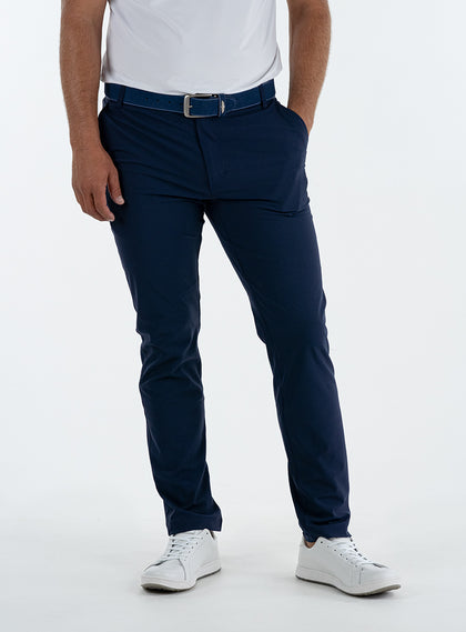 Men's Quest Pant in Indigo, front on-model view featuring navy pants with a button waistband closure and side pockets, styled with a white shirt and white shoes