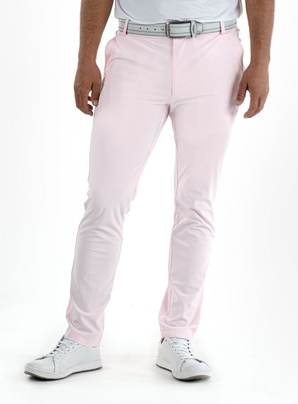 Men's Quest Pant in Light Pink, front on-model view featuring light pink pants with a button waistband closure and side pockets, styled with a white polo, gray belt, and white shoes