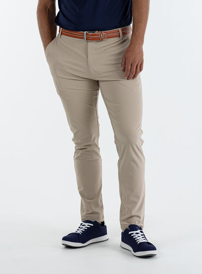 Men's Quest Pant in Light Khaki, front on-model view featuring khaki pants with a button waistband closure and side pockets, styled with a navy shirt, brown belt, and navy shoes