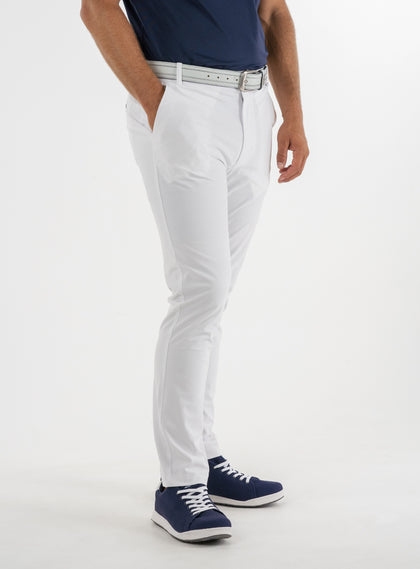 Men's Quest Pant in White, side on-model view featuring white pants with a button waistband closure and side pockets, styled with a navy shirt, gray belt, and navy shoes