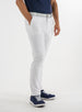 Men's Quest Pant in White, side on-model view featuring white pants with a button waistband closure and side pockets, styled with a navy shirt, gray belt, and navy shoes