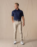 Men's Maverick Twill Pant in Cashew, full length front view on model featuring a solid cashew color paired with a navy polo, navy belt, and white golf shoes