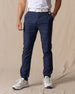 Men's Maverick Twill Pant in New Indigo, front view on model featuring solid navy slim fit golf pants with white belt and white shoes