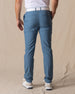 Men's Maverick Twill Pant in Petrol, back view on model featuring solid petrol blue golf pants with white belt and white golf shoes
