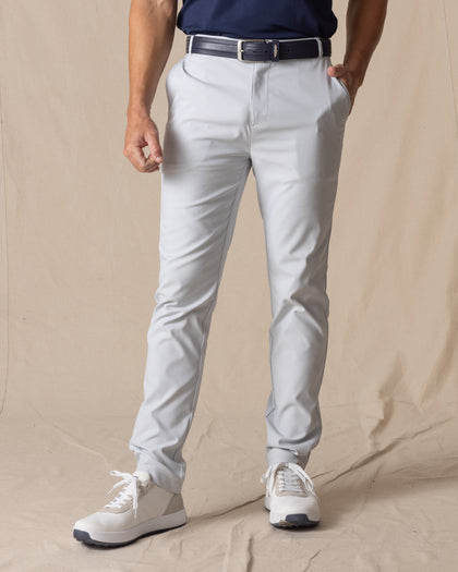 Men's Maverick Twill Pant in Silver, front view on model featuring solid silver slim fit golf pants with navy belt and white golf shoes