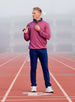 Male model wearing the Men’s Optic Quarter Zip in acai pink, standing on a running track holding a golf club over his shoulder