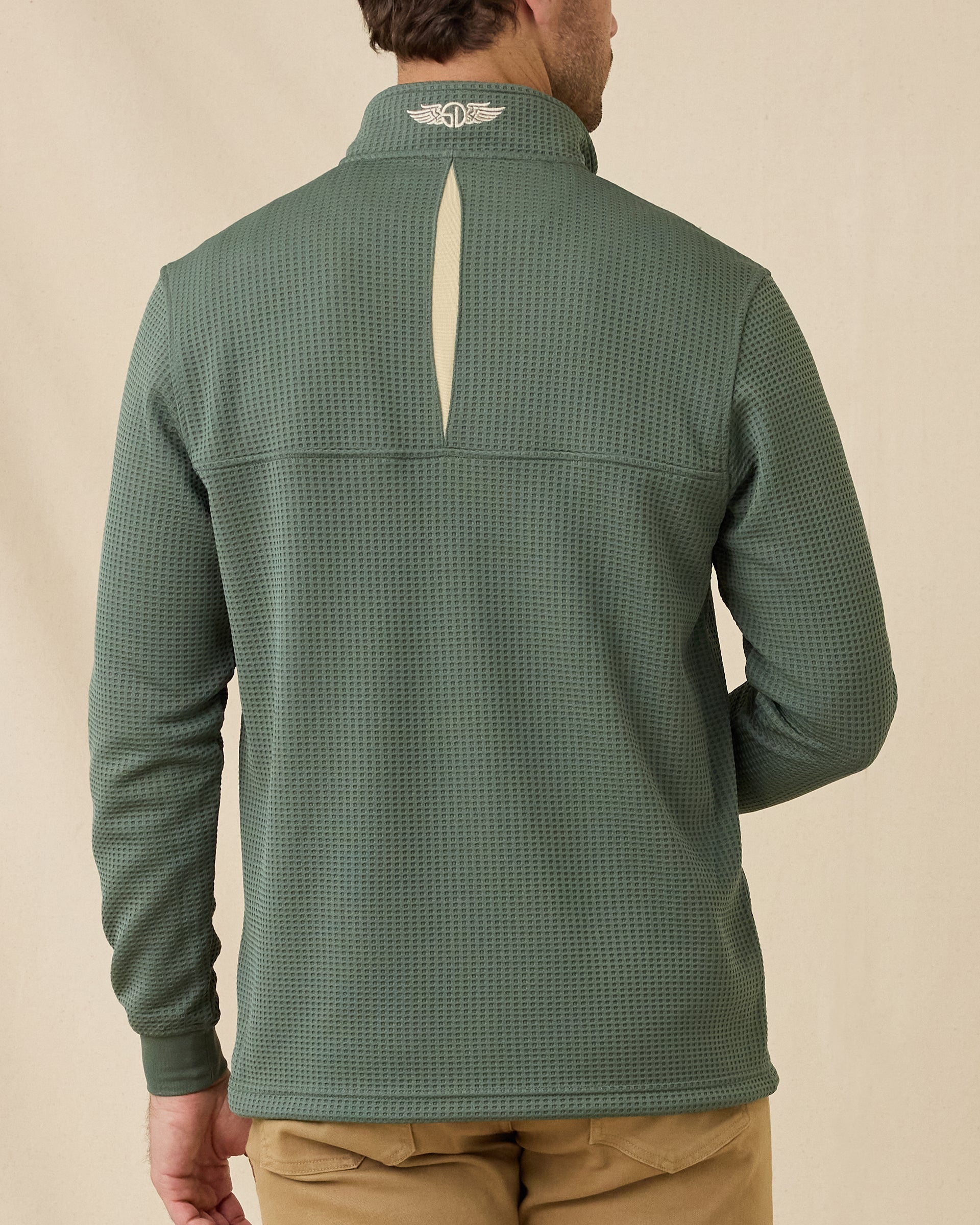 Back view of model wearing the Optic Quarter Zip in Dark Forest, showing the textured waffle knit, contrast back collar detail, and embroidered logo.