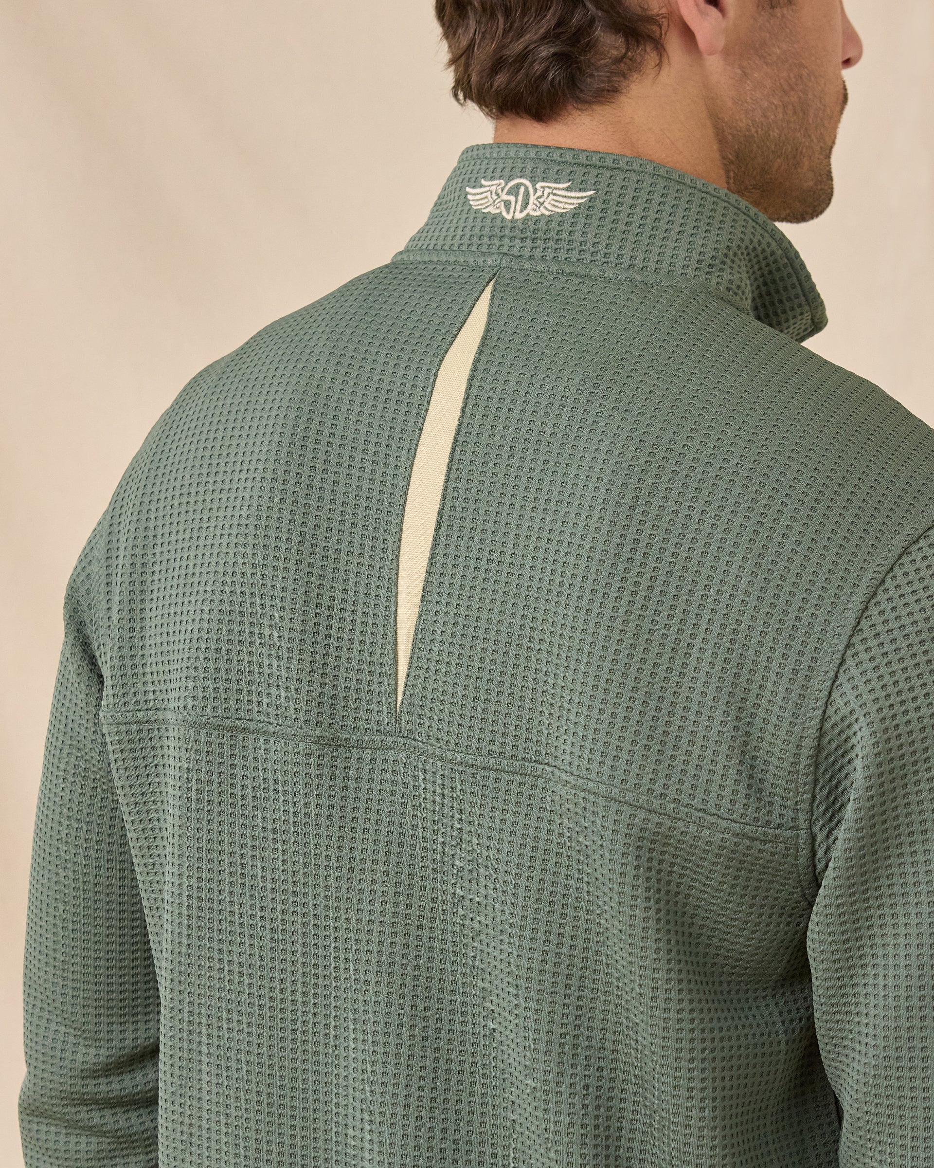 Close-up back view of the Optic Quarter Zip in Dark Forest showing the waffle-knit texture, contrast inset, and embroidered logo at the collar.