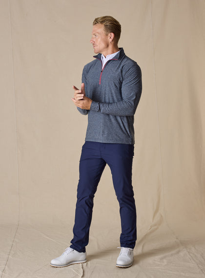Men's Crusher Quarter Zip in New Indigo, full length model view featuring a navy heathered body with red contrast quarter-zip closure, layered over a white collared shirt, styled with navy pants and white shoes
