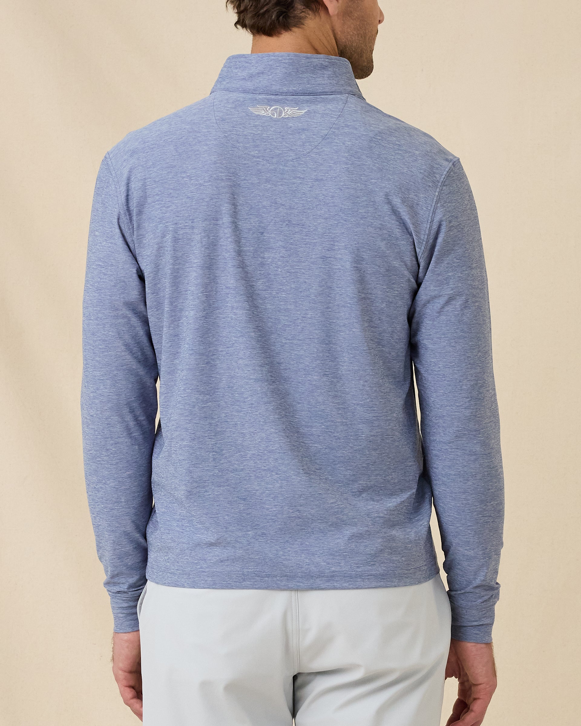 Back view of model wearing the Crusher Quarter Zip in Moonlight, showing the heathered fabric and embroidered logo below the collar.