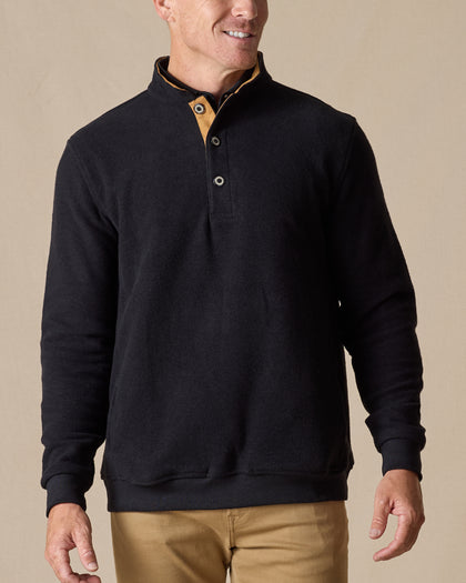 Men's Foothill V2 Placket in Black, on-model front view featuring black fleece fabric, three-button placket with gold suede inner placket trim, layered over a white polo with khaki pants