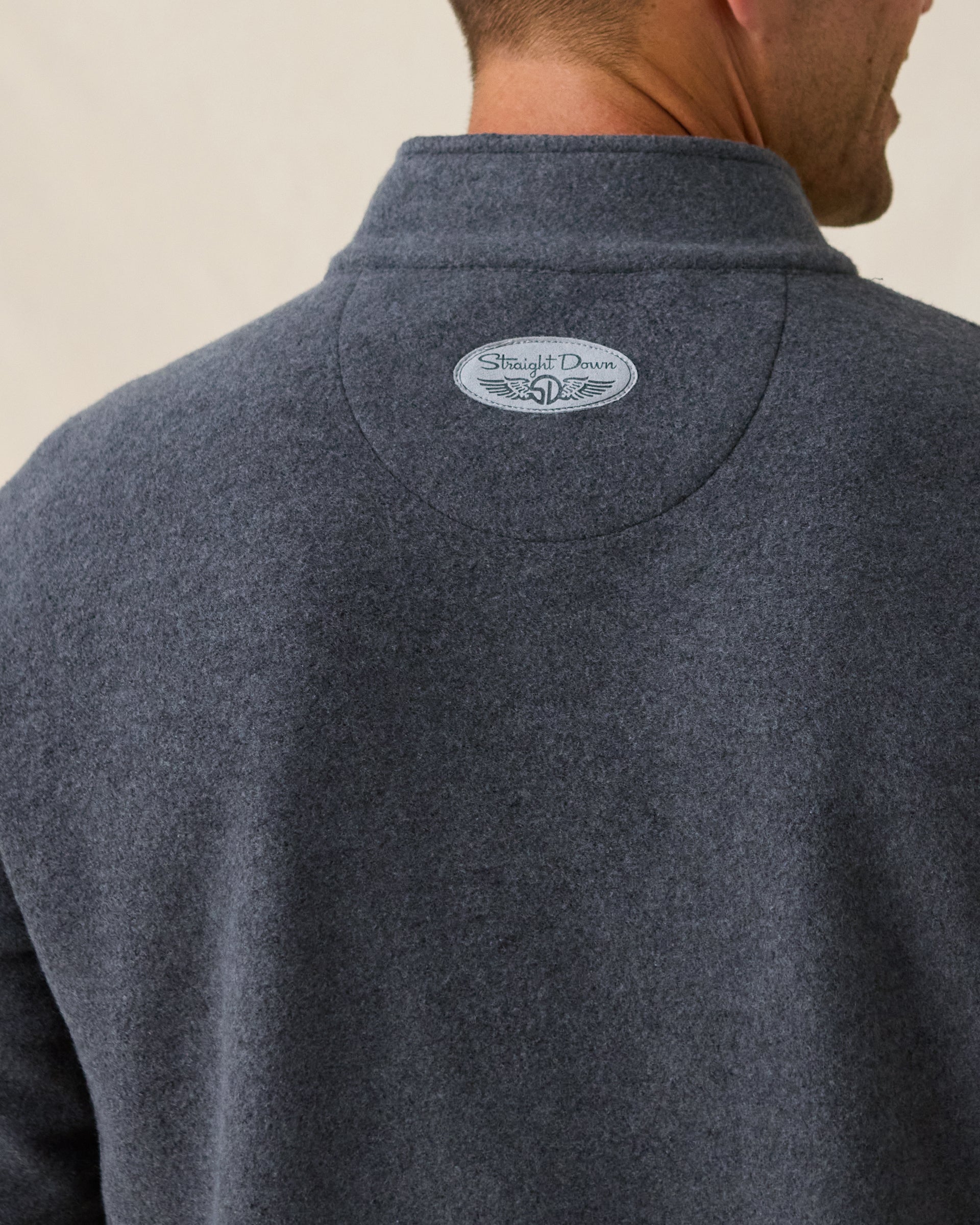 Men's Foothill V2 Placket in Charcoal, close-up back detail view of the Straight Down logo patch centered at the back collar on charcoal heathered fleece