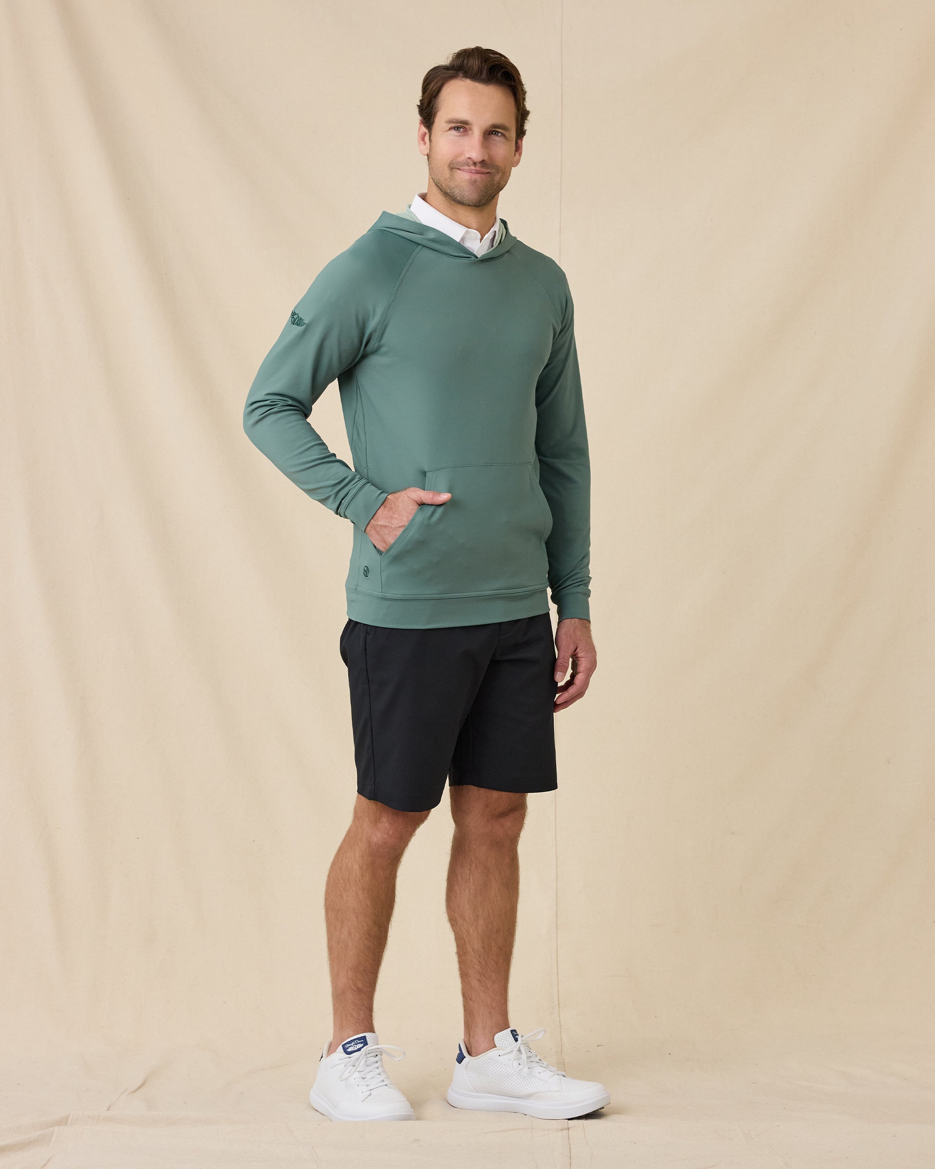 Full-length view of model wearing the Mackenzie Hoodie in Dark Forest with black shorts and white sneakers.
