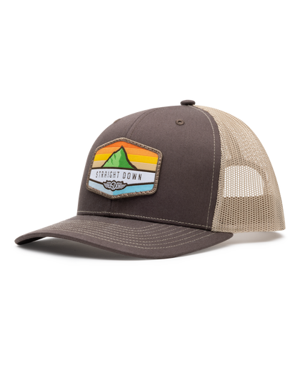 El Toro Hat in Brown, side view featuring a brown structured trucker cap with a woven mountain sunset landscape patch and Straight Down logo on the front panel, with tan mesh back panels and tan contrast stitching on the brim
