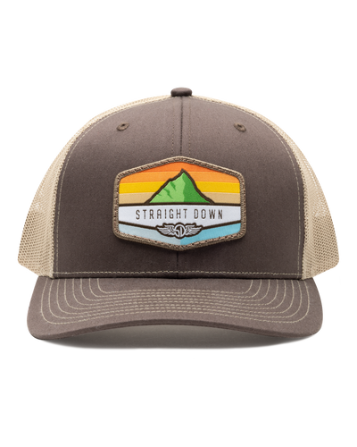 El Toro Hat in Brown, front view featuring a brown structured trucker cap with a woven mountain sunset landscape patch and Straight Down logo on the front panel, with tan mesh back panels and tan contrast stitching on the brim