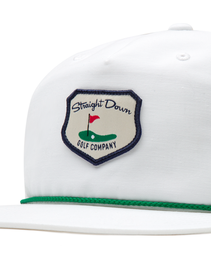 Hogan Retro Rope Hat in White, close-up front detail view highlighting the Straight Down Golf Company navy-bordered shield patch featuring a golf green with flag illustration, with green rope brim detail