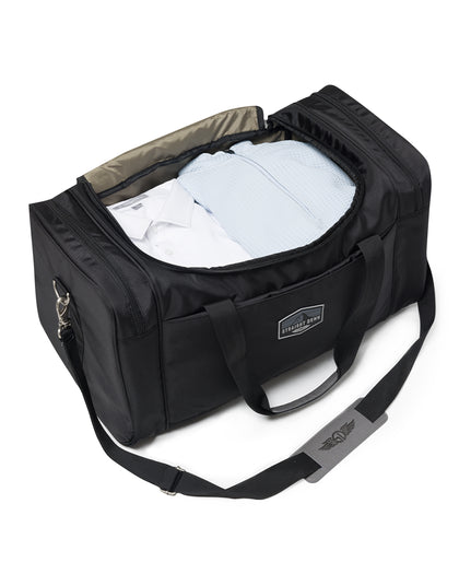 Straight Down Montana Duffle Bag in Black, open top view featuring a black nylon duffle bag packed with folded clothing, showing the gray interior lining and Straight Down logo strap pad